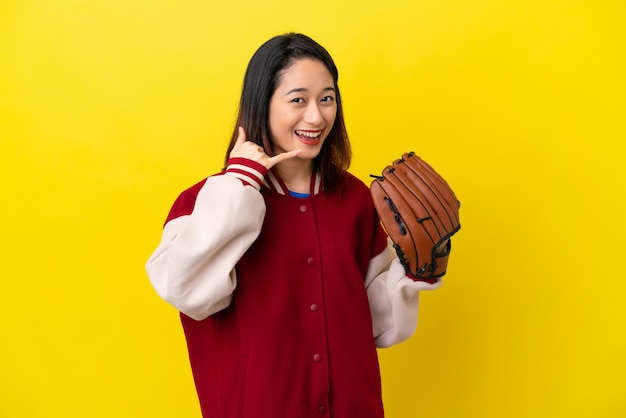Junge vietnamesische Spielerin mit Baseballhandschuh isoliert auf gelbem Hintergrund mit Telefongeste Ruf mich zurück