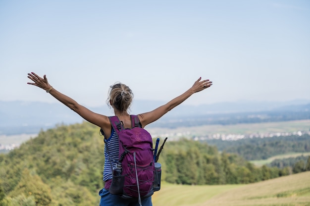 Junge Wanderin, die das Leben mit hoch erhobenen Armen genießt