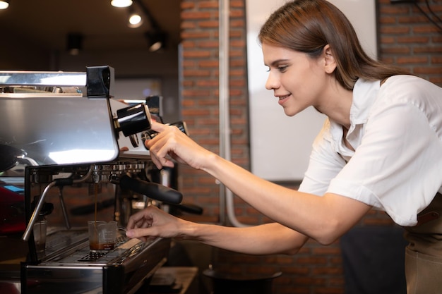 Junge weibliche Barista bereitet Kaffee in einem Café vor Weibliche barista benutzt eine Kaffeemaschine