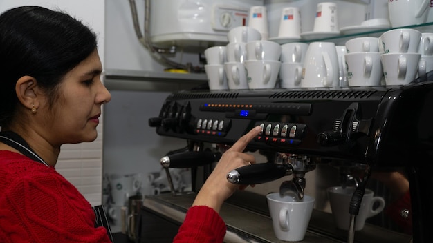 Junge weibliche Barista, die Kaffee in einer Espresso-Maschine macht