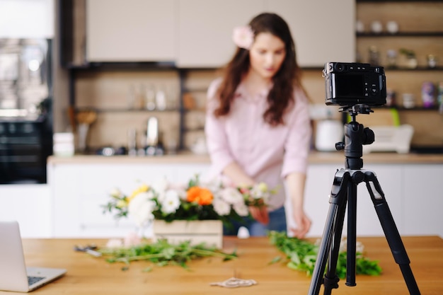 Junge weibliche Floristen zeichnen Video-Tutorial von Blumenkompositionen auf, die vor der Kamera entworfen werden