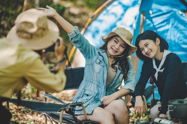 Junge weibliche Fotografen genießen es, ihre Freunde zu fotografieren, sie benutzen Digitalkameras und schöne Mädchen posieren im Campingzelt im Naturwald-Kopienraum