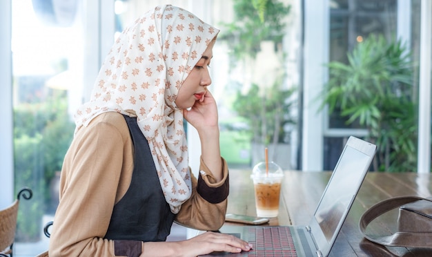 Foto junge weibliche freiberufler tragen hijab mit einem laptop