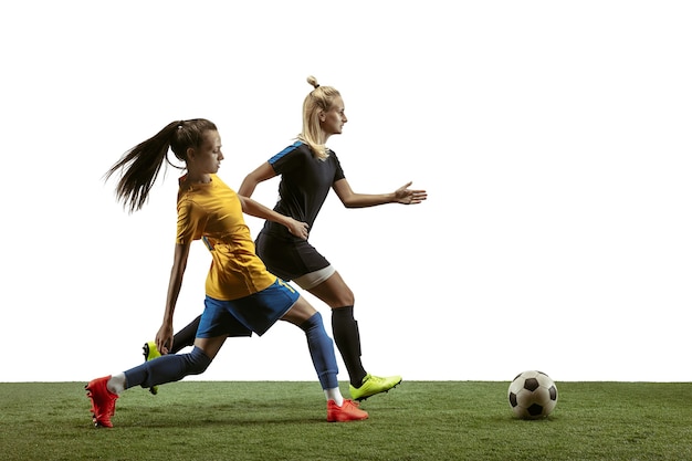 Junge weibliche Fußball- oder Fußballspieler mit langen Haaren in Sportbekleidung und Stiefeltraining auf weißem Hintergrund. Konzept eines gesunden Lebensstils, Profisport, Bewegung, Bewegung. Kampf ums Tor.