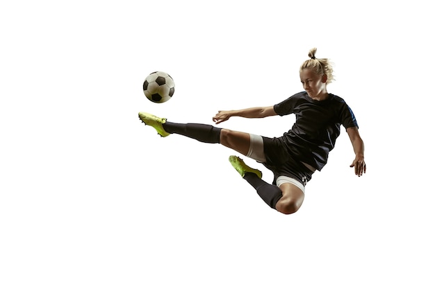Junge weibliche Fußball- oder Fußballspielerin mit langen Haaren in Sportbekleidung und Stiefeln, die Ball treten
