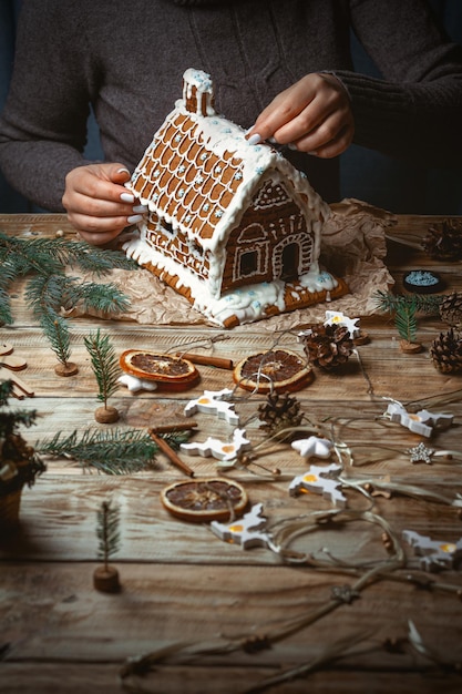 Junge weibliche Hände schmücken das Weihnachtslebkuchenhaus