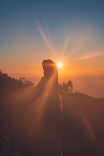 Junge weibliche Konfrontation mit Sonnenaufgang auf dem Berggipfel im tropischen Regenwald im Nationalpark