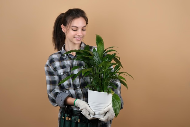 Junge weibliche lächelnde Gärtnerin mit Topf mit grüner Pflanze auf farbigem Hintergrund Konzept der Berufsberatung für Jugendliche