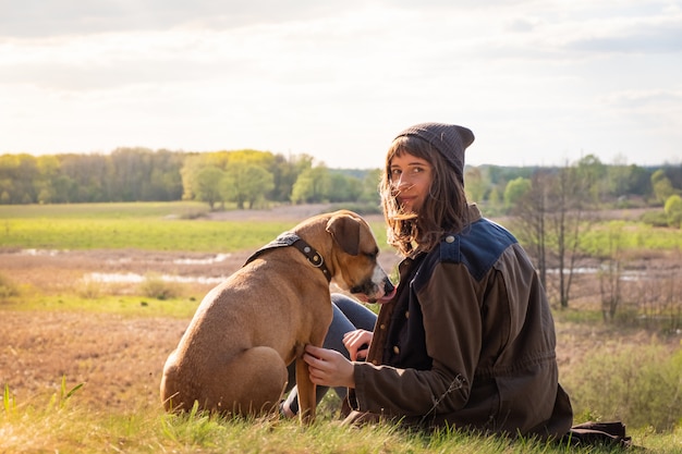 Foto junge weibliche person zusammen mit staffordshire terrier auf der wiese am warmen sonnigen nachmittag