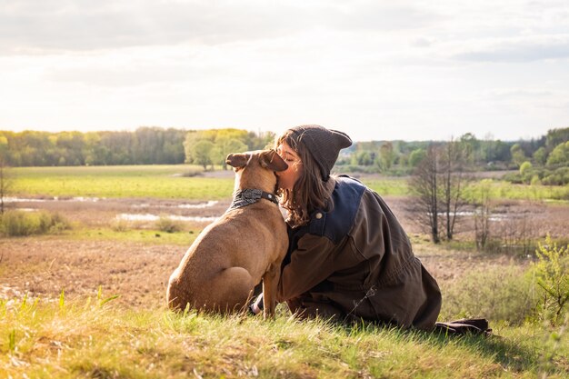 Junge weibliche Person zusammen mit Staffordshire Terrier auf der Wiese am warmen sonnigen Nachmittag