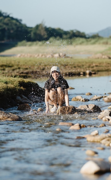 Junge weibliche Reisende genießen und spritzen Wasser während der Reise im Tal