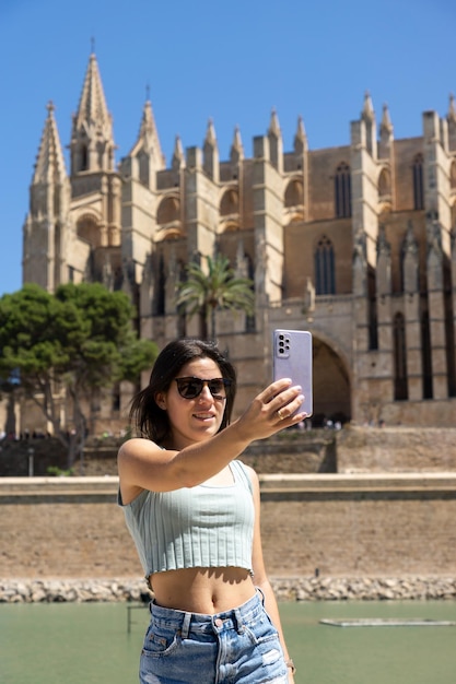 Junge weibliche Touristen, die ein Foto mit ihrem Handy in der Kathedrale von Palma de Mallorca in Spanien machen