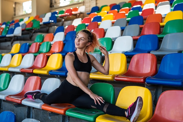 Junge weibliche Trainerin, die Yoga-Übungen im Stadionsport für einen gesunden Lebensstil macht