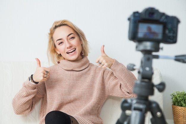 Junge weibliche Vloggerin neben Videokamera zu Hause