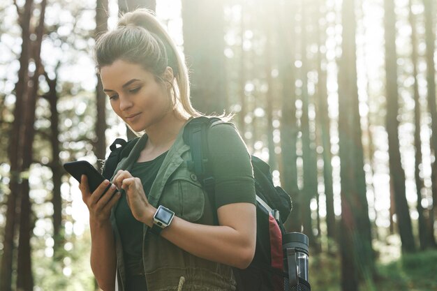 Junge weibliche Wanderer benutzt Smartphone für die Navigation im grünen Wald