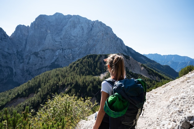 Junge weibliche Wandererin mit einem Rucksack, der anhält, um die schöne Ansicht der Berge zu betrachten.