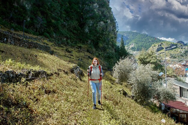 Junge weiße Frau benutzt einen Wanderstock, während sie einen Hang in der Nähe des Ferienortes Fethiye in der Türkei erklimmt