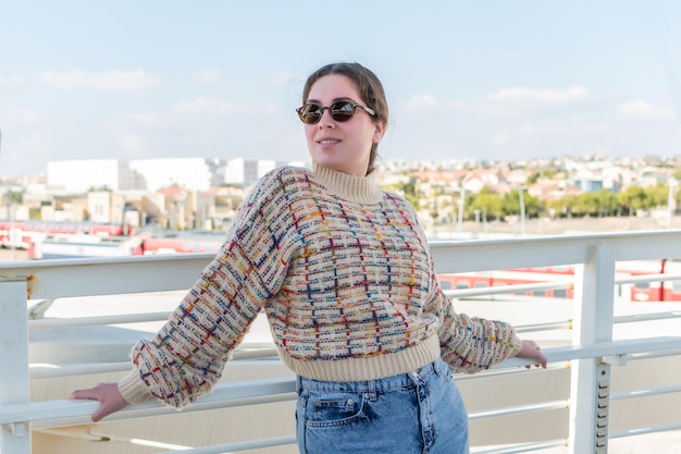 Junge weiße Frau, die auf einer Brücke steht und an einem sonnigen Herbsttag eine Sonnenbrille trägt. Ein Volk