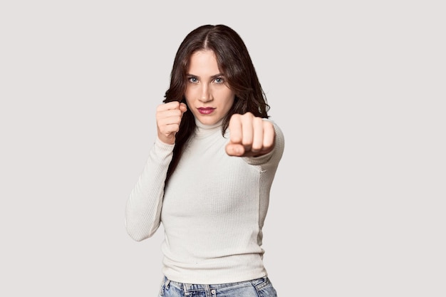 Junge weiße Frau in einem Studio schlägt Wut und kämpft wegen eines Streits im Boxen