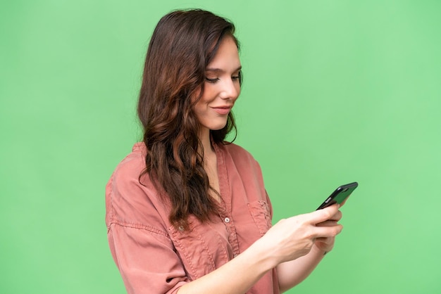 Junge weiße Frau mit isolierter Herkunft sendet eine Nachricht oder eine E-Mail mit dem Handy