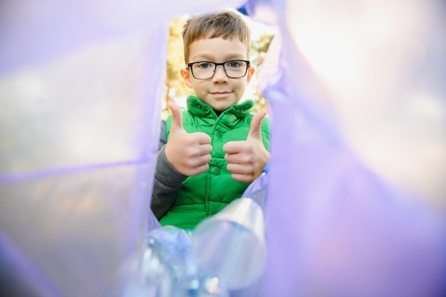 Foto junge wirft plastikmüll in eine tüte im park