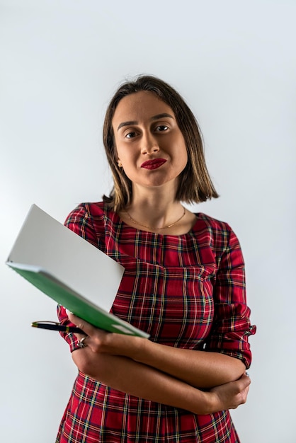 Junge Wirtschaftslehrerin mit Brille, die ein Buch isoliert auf einem typischen Hintergrund hält