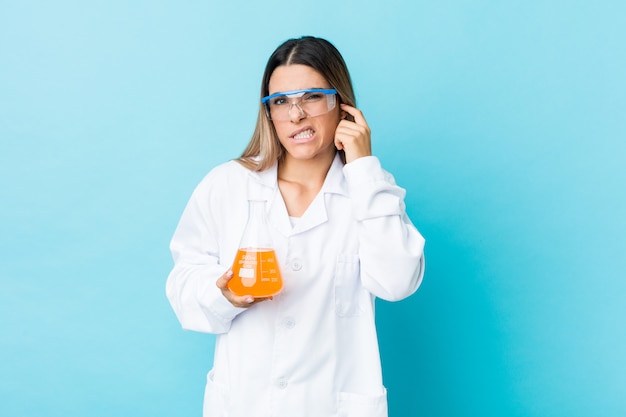 Junge wissenschaftliche Frau, die Ohren mit den Händen bedeckt.