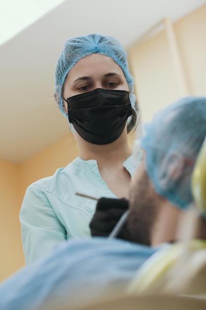 Junge Zahnärztin bei der Arbeit im Büro mit Patientin, Nahaufnahme