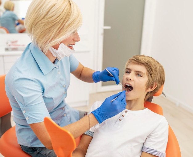Junge Zahnärztin, die Jungenzähne untersucht