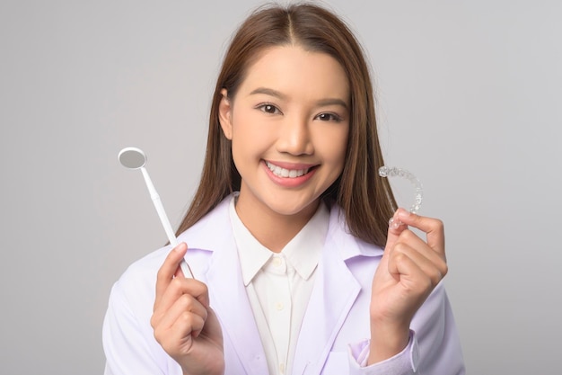 Junge Zahnärztin mit Invisalign-Klammern über weißem Hintergrund Studio Dental