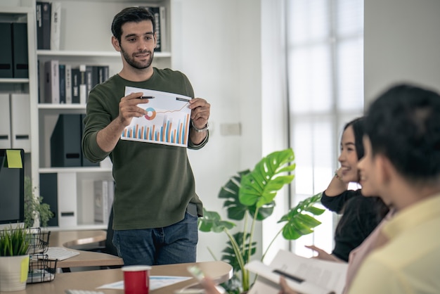 Jungen Geschäftsleuten wird dem Kunden im Büro des Besprechungsraums ein Marketingarbeitsprojekt vorgestellt