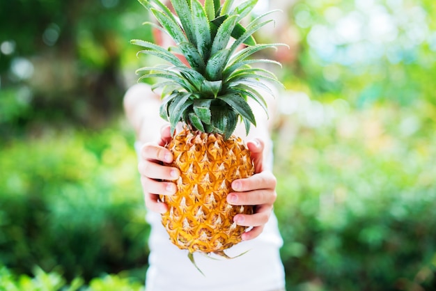 Jungen-Griff-Ananas übergibt Sommer