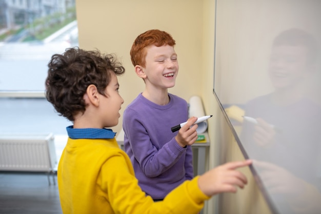 Foto jungen lachen und schreiben auf das whiteboard