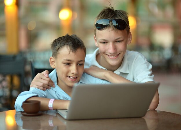 Jungen sitzen mit Laptop und Kaffee im Hotel