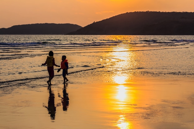 Jungen und Mädchen spielen am Strand in der Abendsonne.