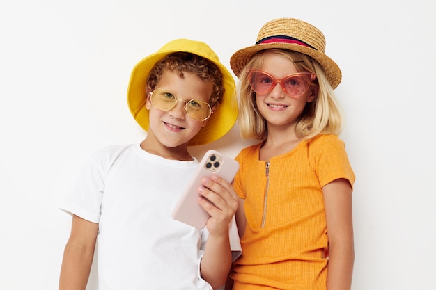 Jungen und Mädchen tragen Hüte mit Telefonmode, die Kindheit posieren