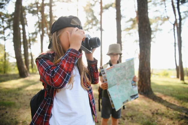 Foto jungen und mädchen wandern mit rucksäcken auf der waldstraße an einem sonnigen tag