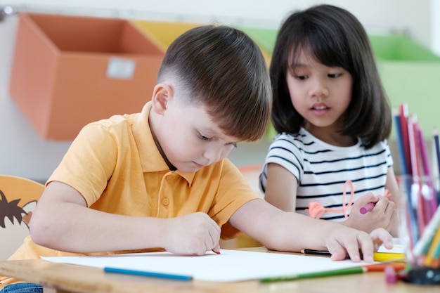 Jungen- und Mädchenzeichnungsfarbbleistifte im Kindergartenklassenzimmer