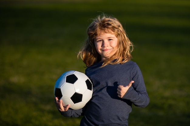 Jungenkind, das Fußball auf Fußballplatz spielt Kind, das Fußball spielt, zeigt Daumen nach oben Erfolgszeichen Training für Sportkinder