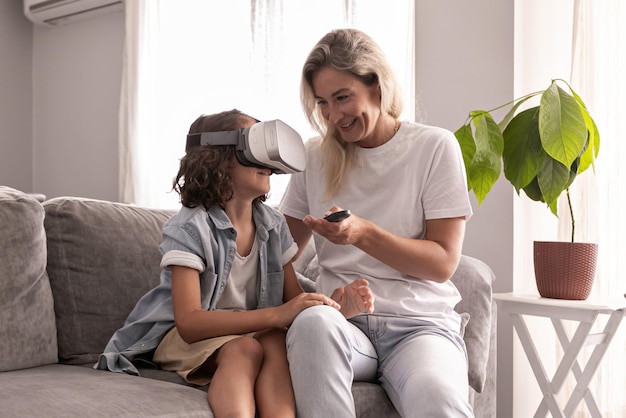 Jungenkind, das virtual-reality-headset mit seiner mutter-vr-brille im wohnzimmer zu hause trägt und spaß hat