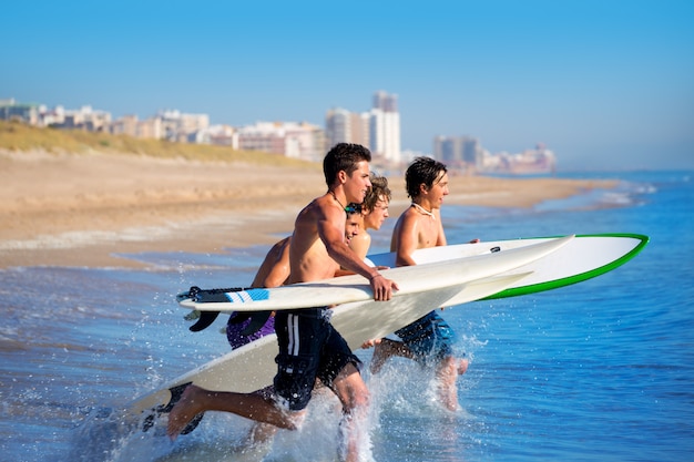 Jungensurfer, die das Laufen springend auf Surfbretter surfen