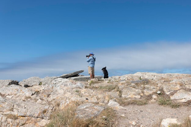 Junger Abenteurer fotografiert mit seinem Hund entlang der Klippe