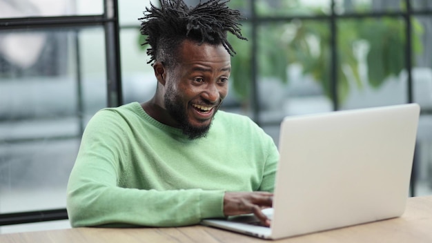Junger afrikanisch-amerikanischer Geschäftsmann, der im Loft-Büro oder Café sitzt und an einem neuen Online-IT-Start arbeitet