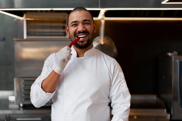 junger afrikanischer Chef, der in der Berufsküche im Restaurant zubereitet eine Mahlzeit steht