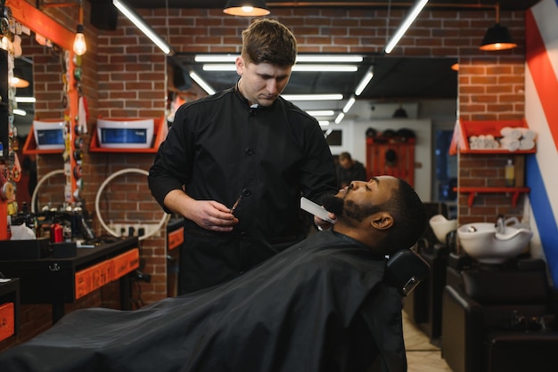 Junger afrikanischer Kerl, der neuen Friseur im Friseursalon erhält