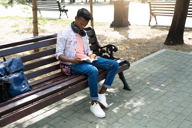 junger afrikanischer mann, der ein buch im park liest