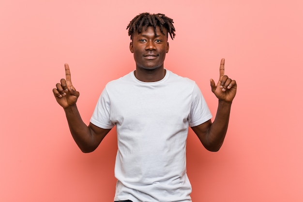 Junger afrikanischer schwarzer Mann zeigt mit beiden Vorderfingern an, die sich ein Leerzeichen zeigen.
