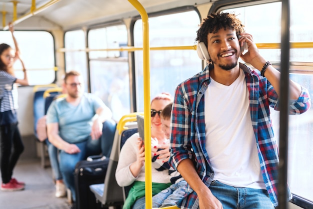 Foto junger afrikanischer typ, der die musik hört, während in den öffentlichen verkehrsmitteln reitend.