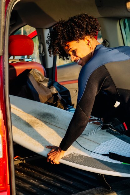 Junger afroamerikaner mit einem surfbrett im wohnmobil