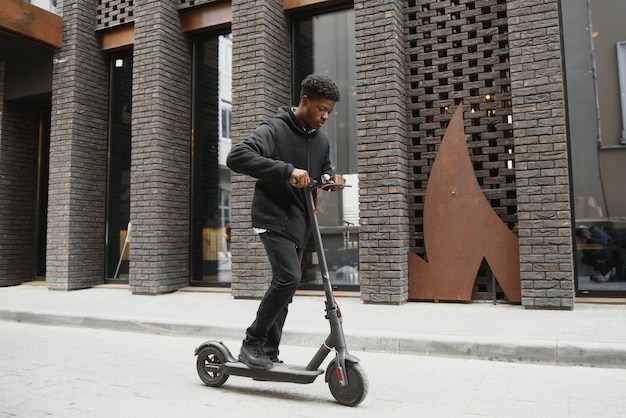 Junger Afroamerikaner mit Elektroroller in der Stadt